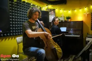 Взрослый ученик играет на виолончели, концертмейстер за пианино улыбается ему из-за нот – Вечер виолончели, апрель 2026